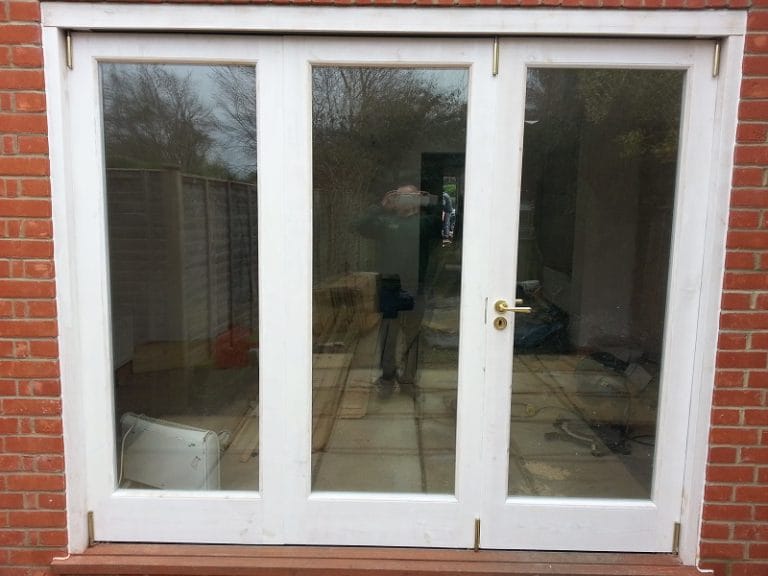 White timber French doors with a garden view through the glass
