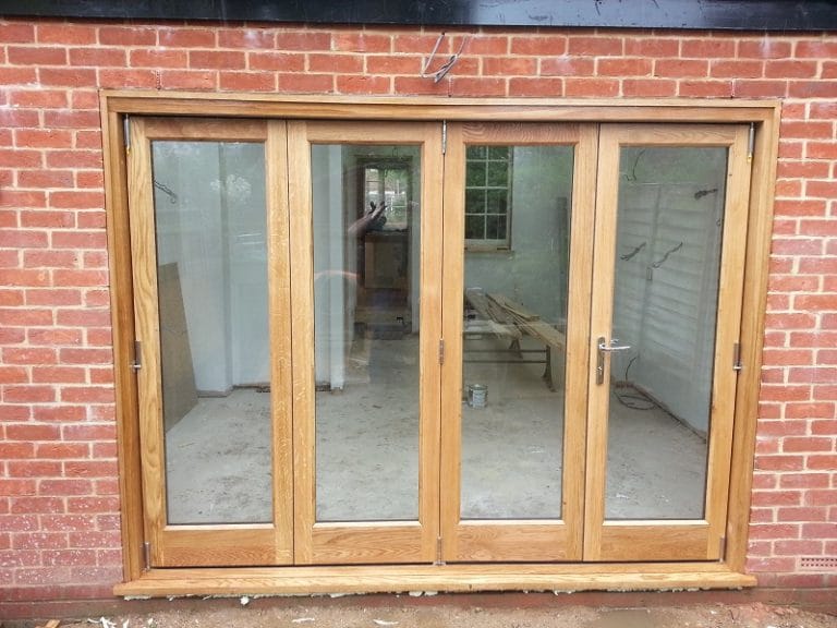 Natural timber folding doors across a wide brick opening