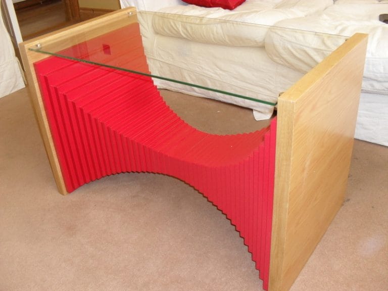 Red layered sculptural table base under a glass top