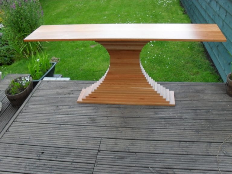 Timber garden table with a waisted stepped base on decking