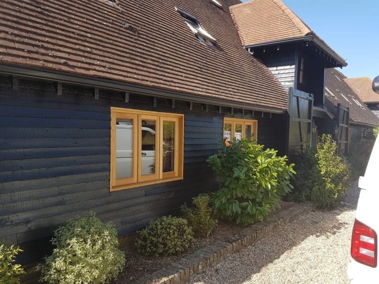 Natural timber casement windows on a black weatherboarded barn