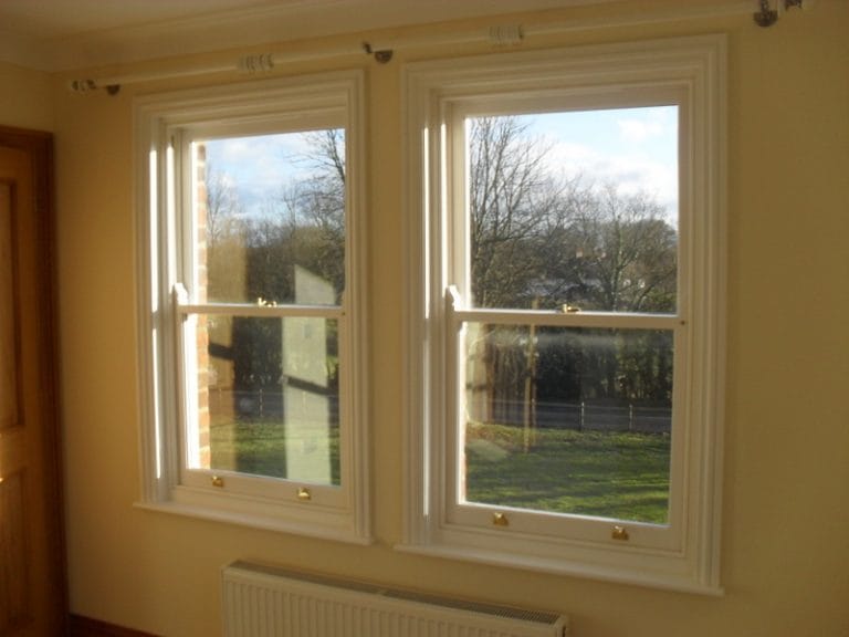 Cream timber casement windows with a tree view, seen from inside