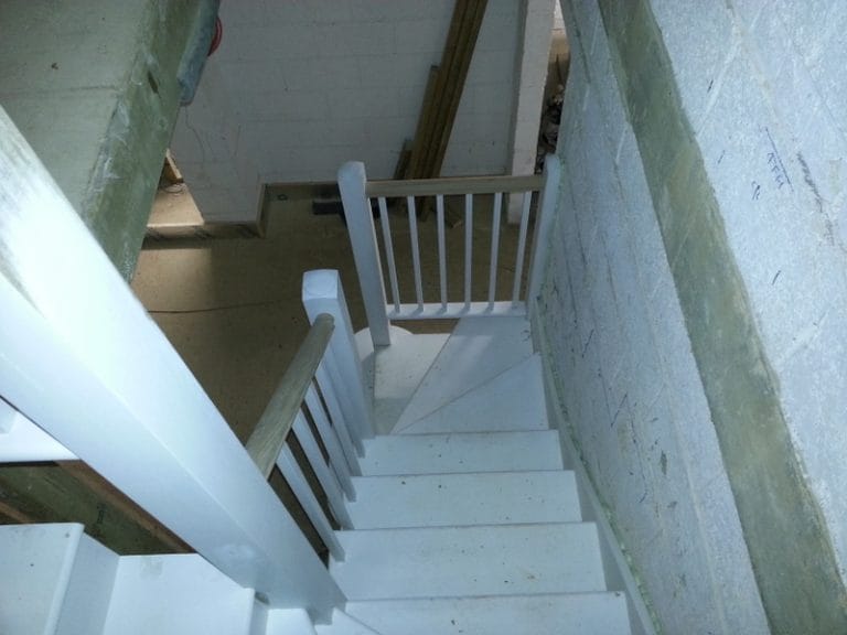 White painted stairs rising beside a whitewashed brick wall