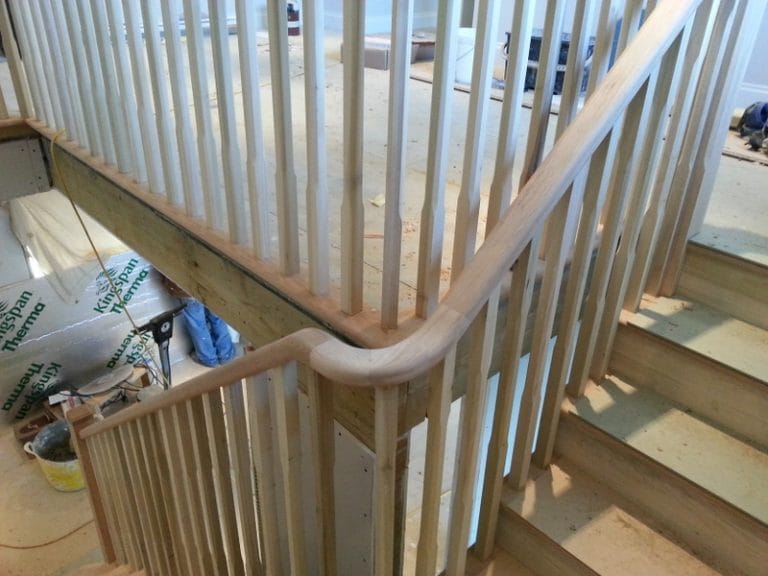 Curved timber handrail on a staircase with white spindles