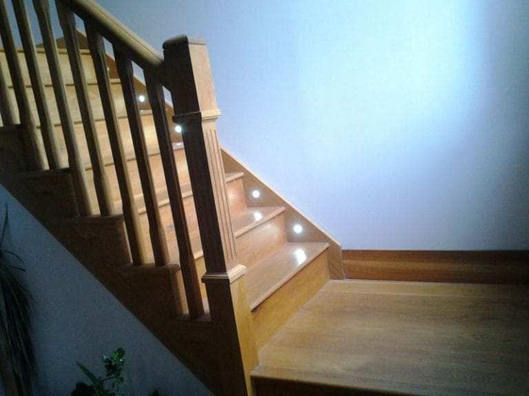 Dark timber staircase with lit treads and white walls