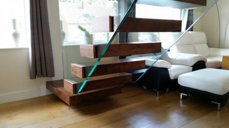 Floating dark timber staircase beside a white sofa