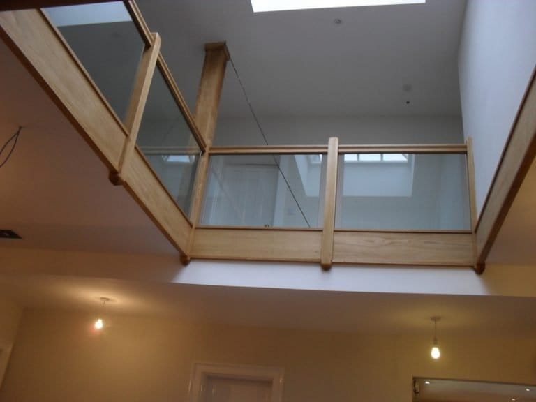 Timber and glass gallery balustrade over a lit stairwell