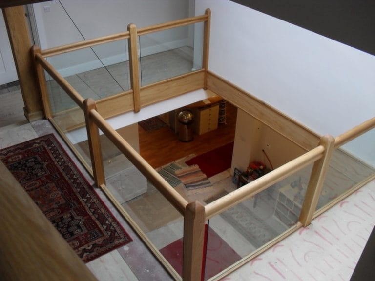 Timber and glass gallery overlooking a hallway with a rug