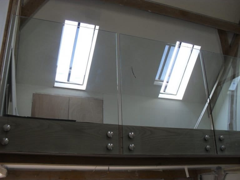 Frameless glass balustrade on a landing beneath roof lights