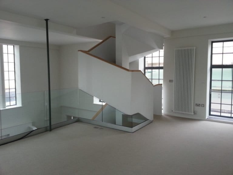 Modern staircase with glass balustrade in a white open plan room