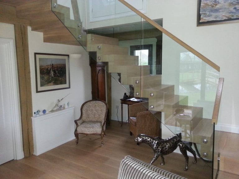 Floating timber staircase with a glass balustrade in a furnished hall