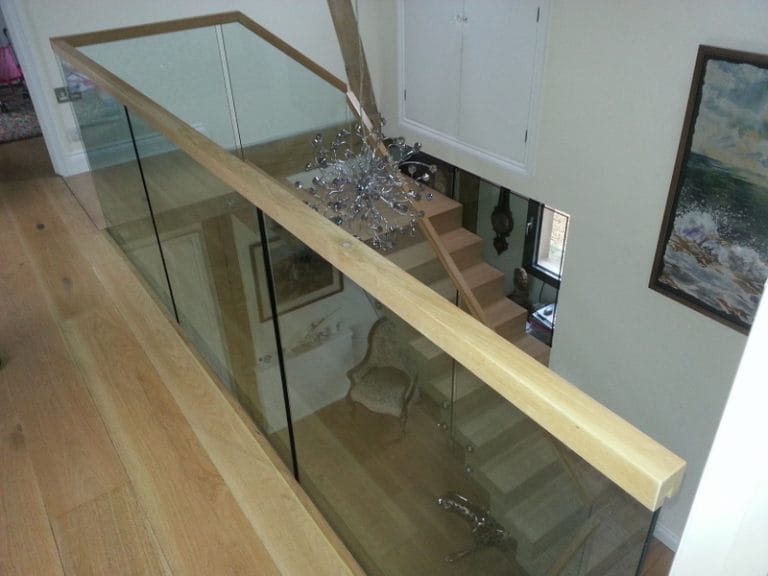 Timber handrail on a glass balustrade running down a staircase
