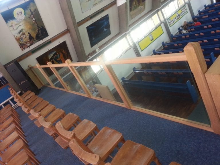 Timber and glass gallery balustrade above church seating