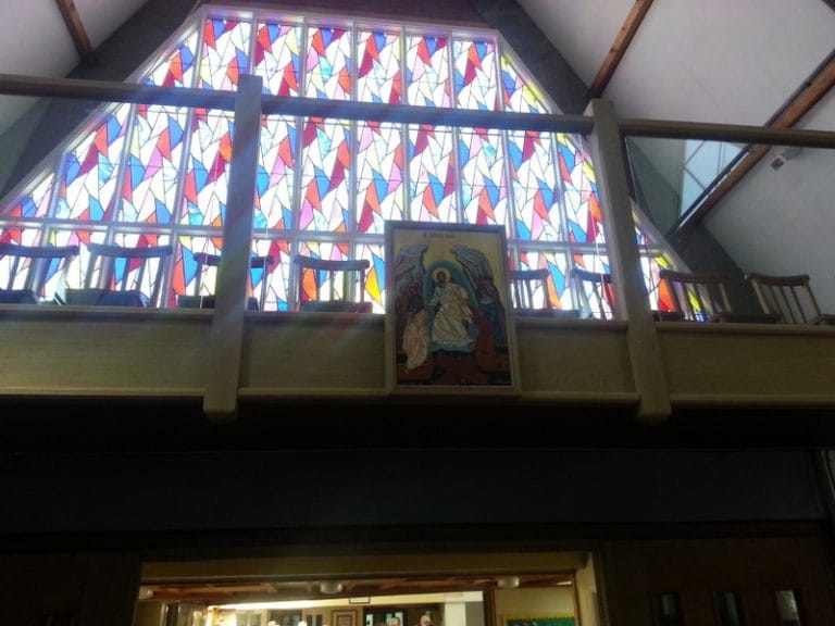 Timber gallery with a religious icon beneath stained glass