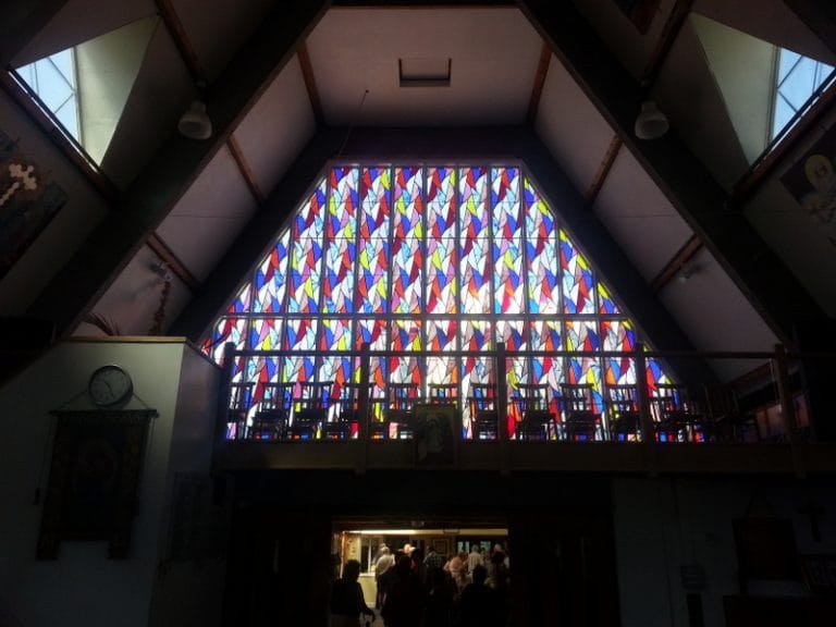 Church interior with a stained glass gable and timber gallery