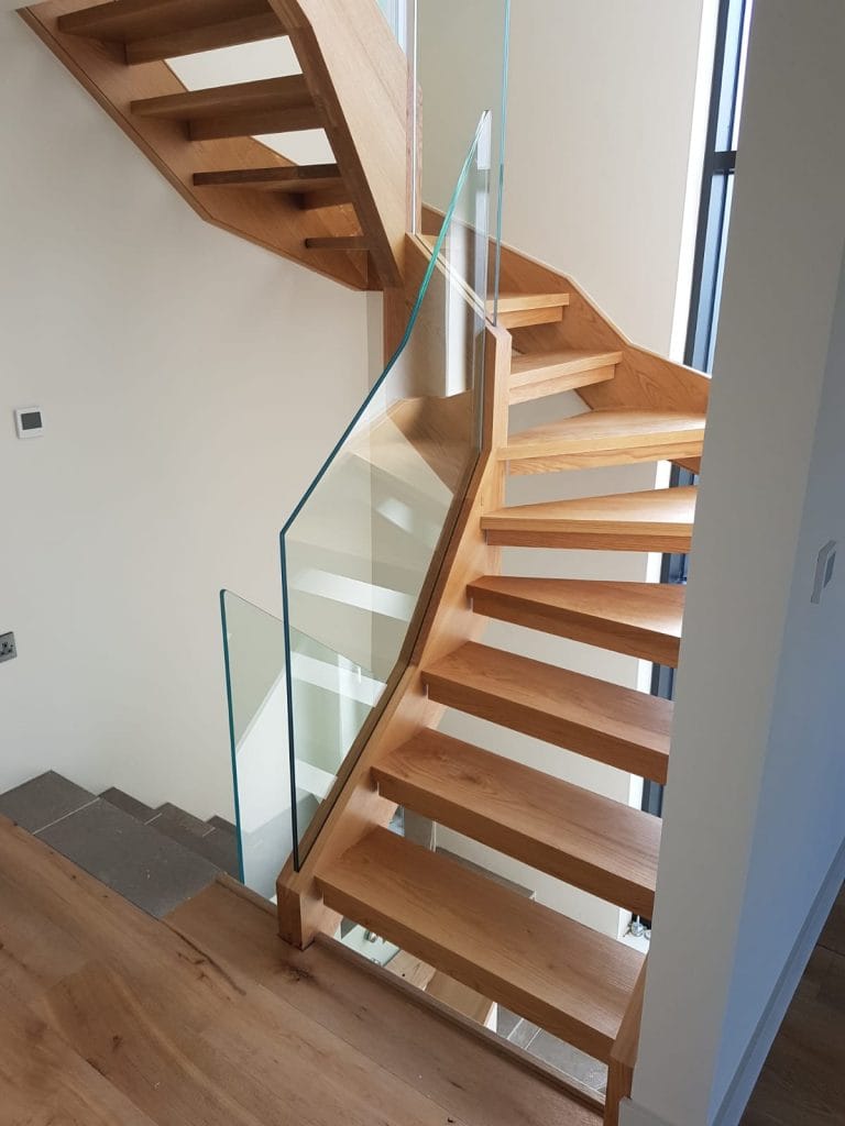 Timber open tread staircase turning beside a glass panel