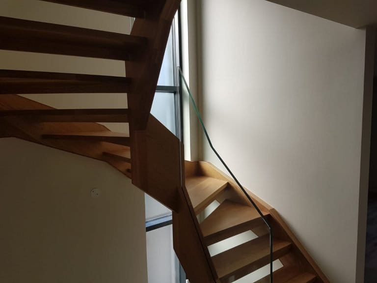 Dark timber spiral staircase with a glass balustrade