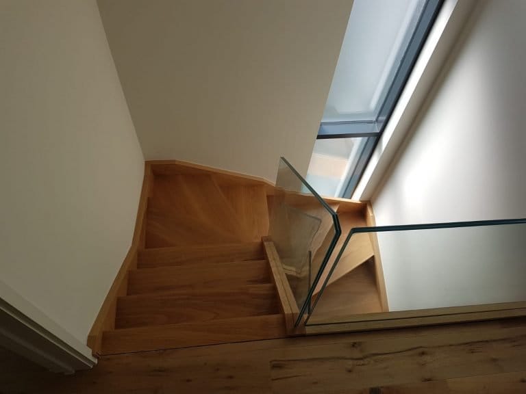 Timber staircase with glass balustrade beneath a roof window