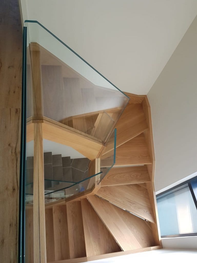 Looking down a timber and glass staircase to the floor below