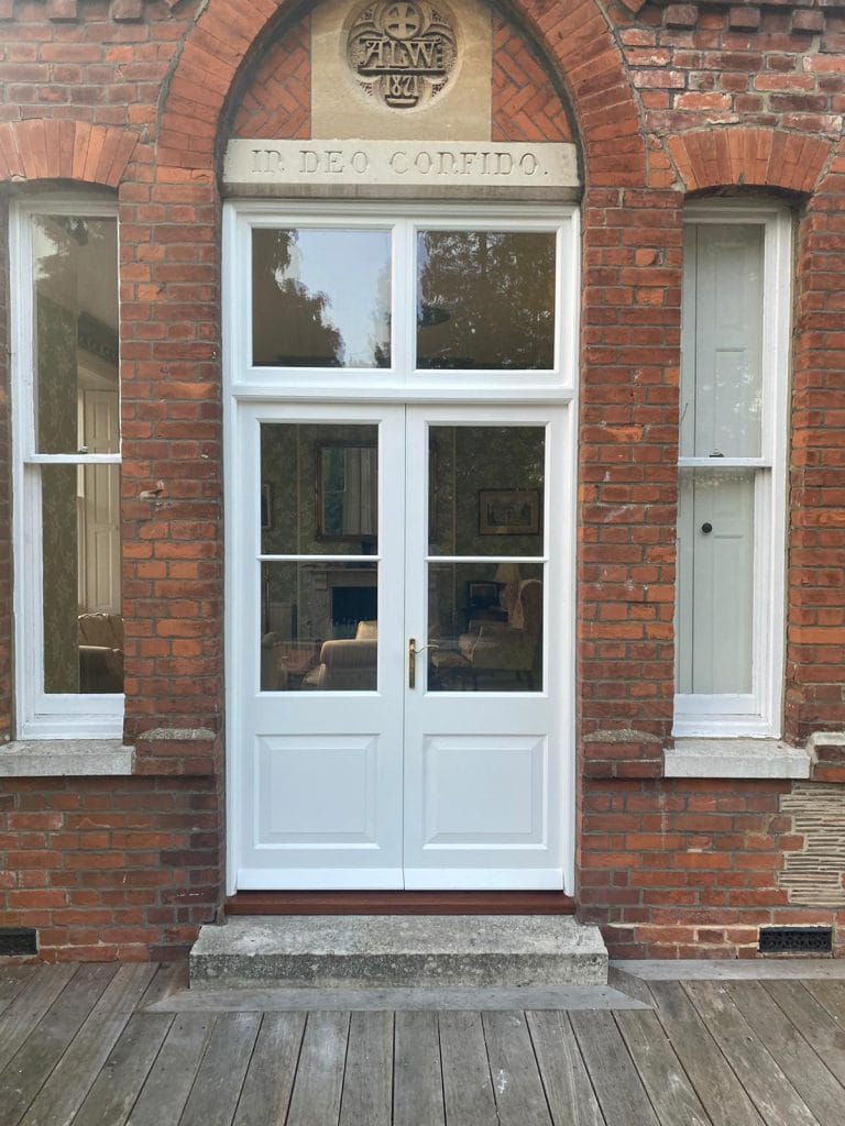 White timber French doors with a fanlight between sash windows