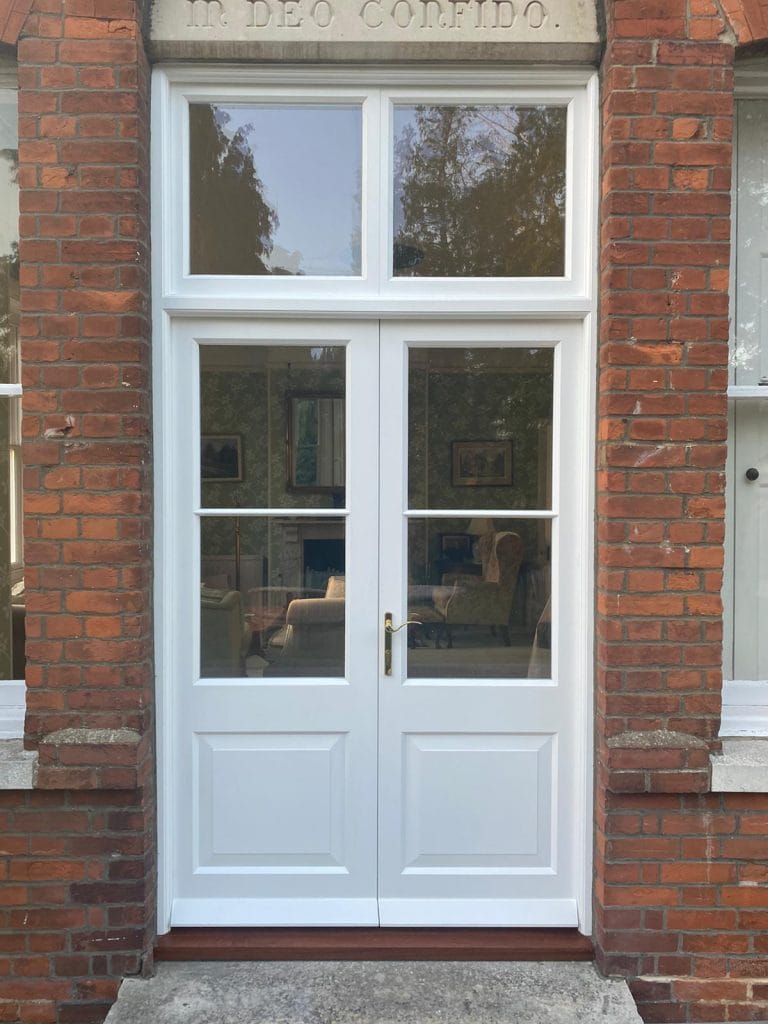 White glazed timber double doors in a red brick wall