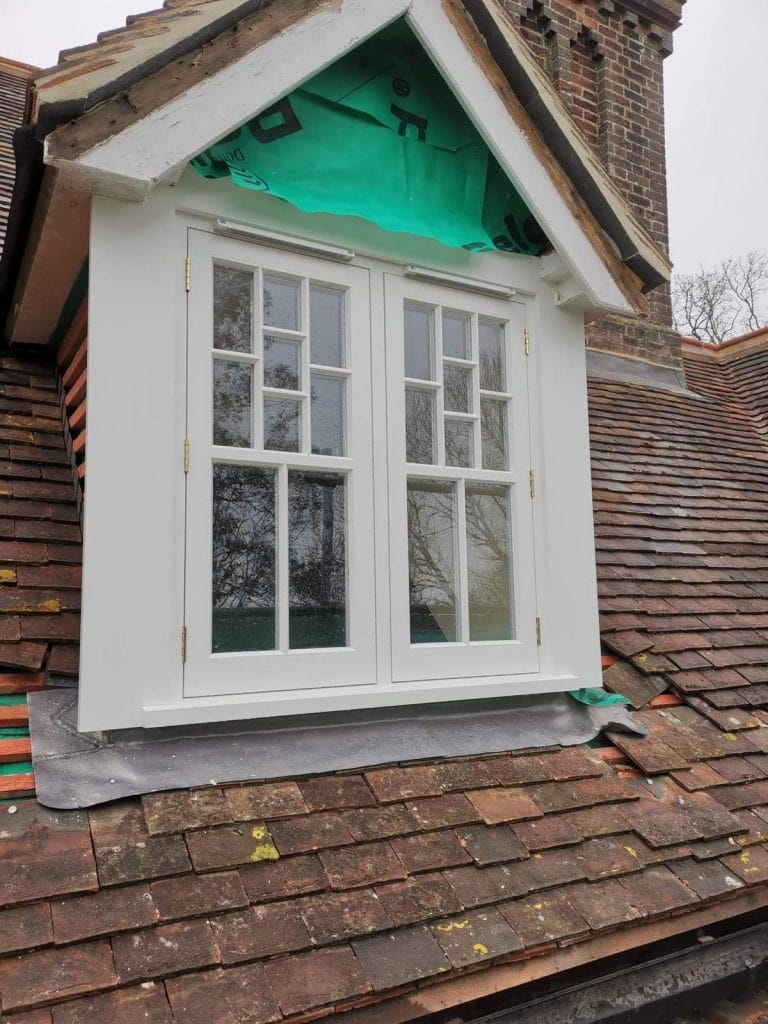 Pair of white timber casement windows in a tile hung wall