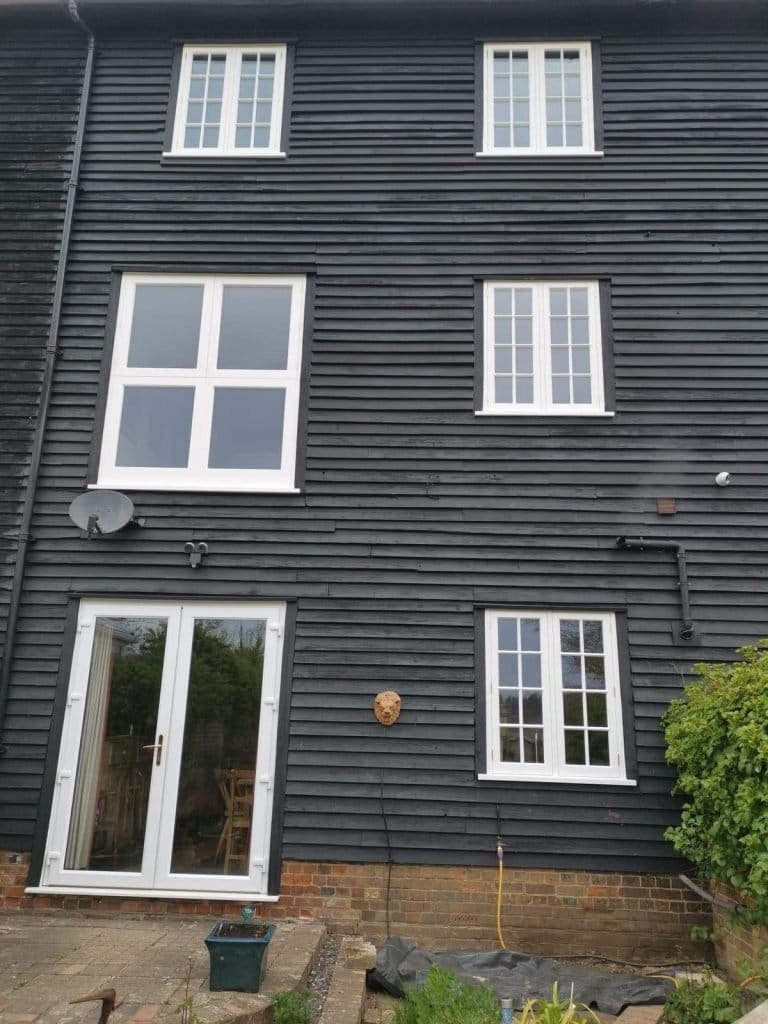 White timber windows on a black weatherboarded house