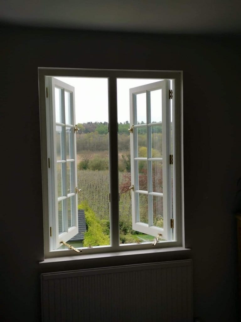 White timber casement windows opening onto a wooded view
