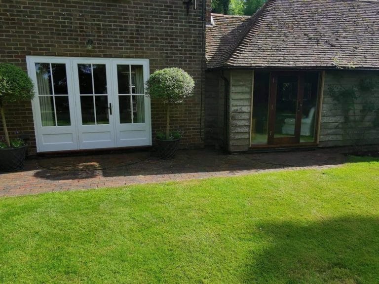 White timber windows on a single storey extension facing a lawn