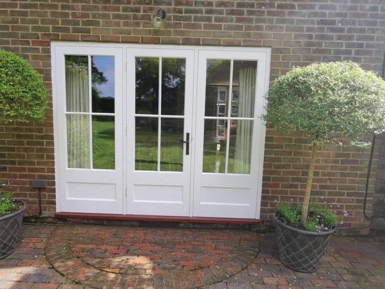 White timber French doors with side windows opening onto a brick terrace