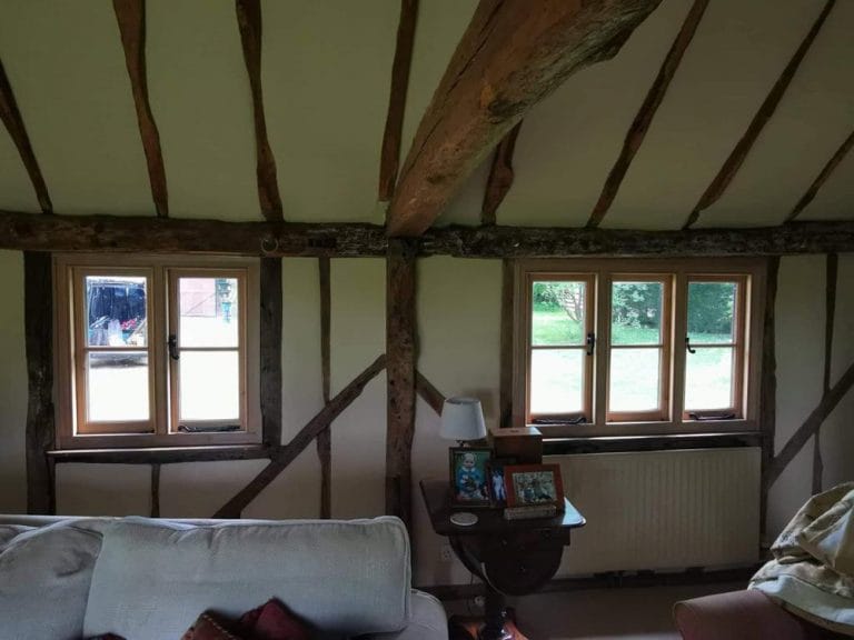 Timber casement windows between exposed beams in a cottage room