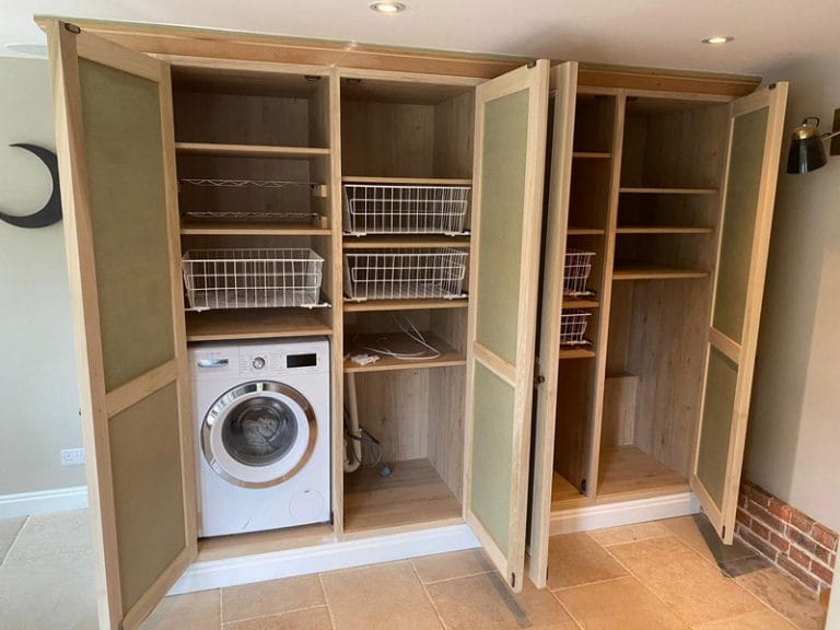 Fitted utility cupboard opened to show washing machine and shelves
