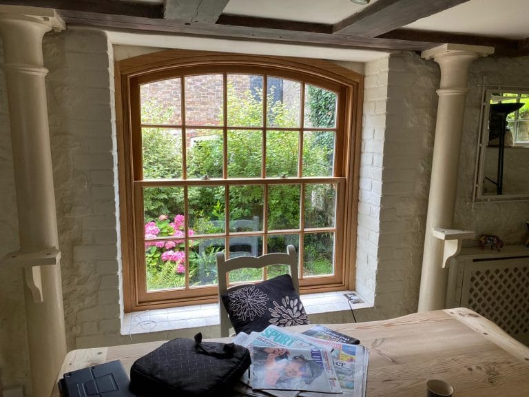 Arched timber window with small panes, viewed from inside