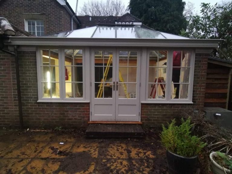 White timber orangery with French doors and a lantern roof