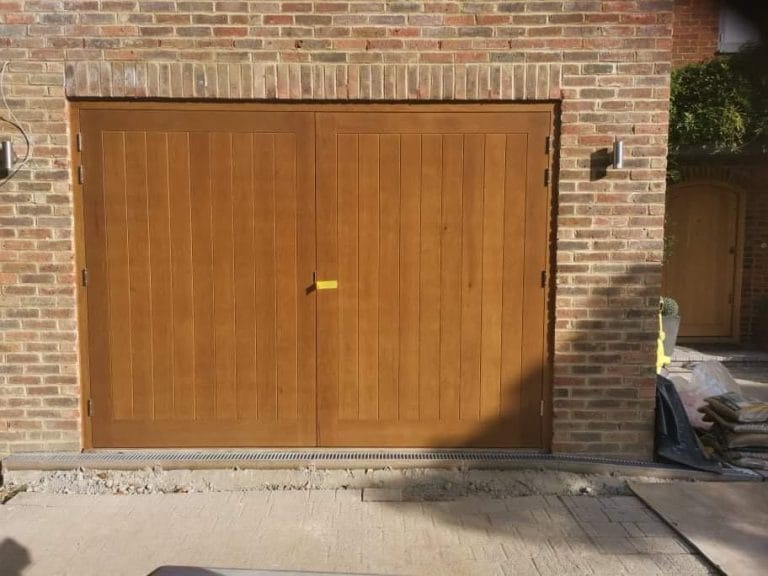 Wide natural timber garage door set in buff brickwork