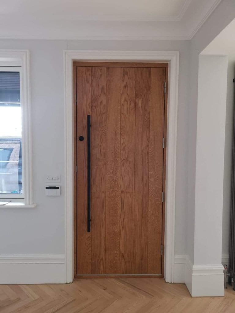 Vertical boarded timber door with a long black pull handle