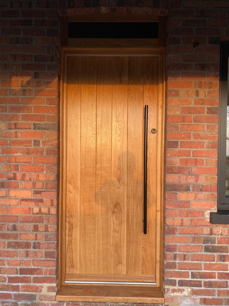 Light timber entrance door with vertical boards and a long handle