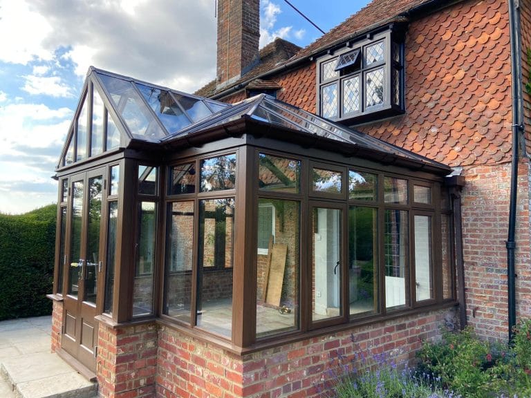 Hardwood conservatory with glazed gables beside a lawn