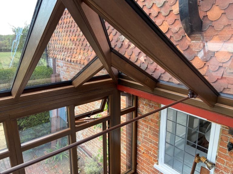 Corner of a timber conservatory roof meeting the house wall