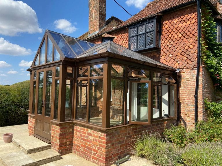 Side view of a stained timber conservatory against brickwork