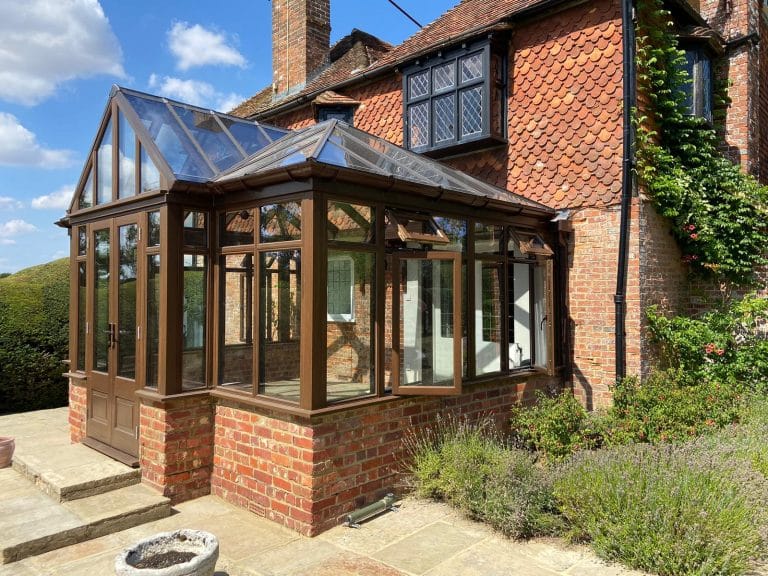 Hardwood conservatory on a brick house with a gabled glass roof