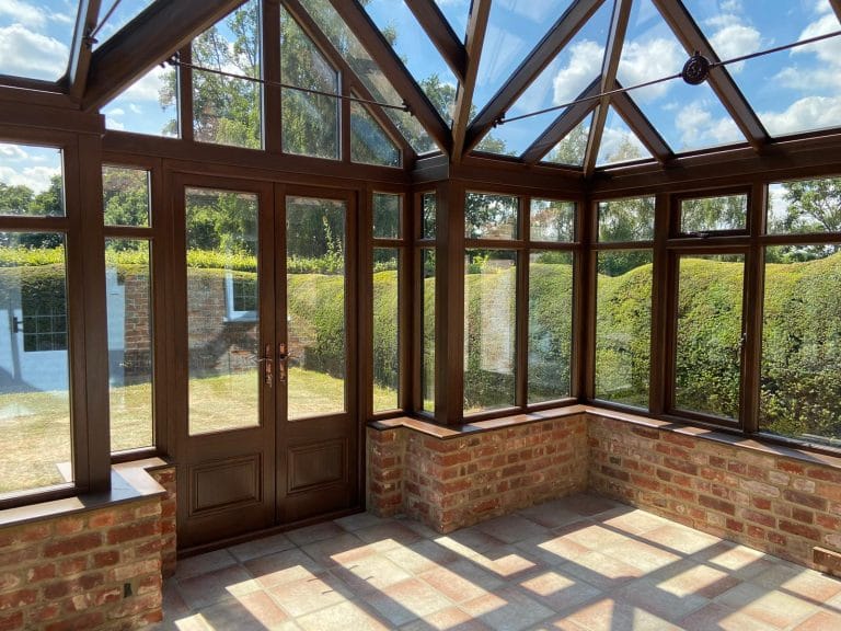 Inside a stained timber conservatory looking out to the garden