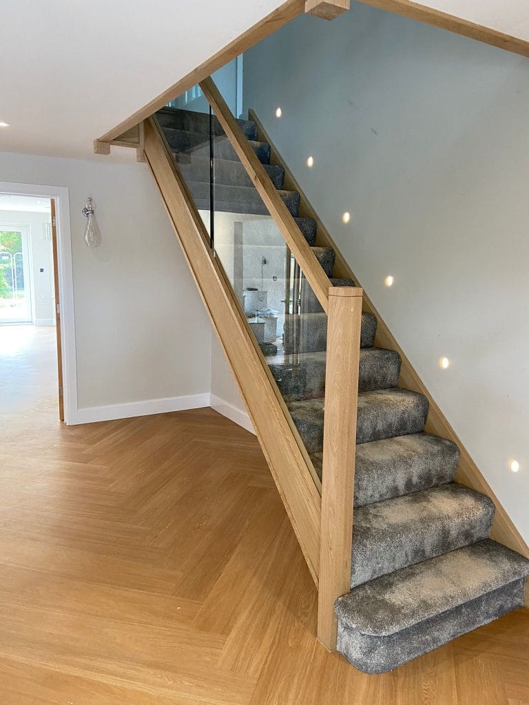 Timber staircase with glass infill panels and carpeted treads