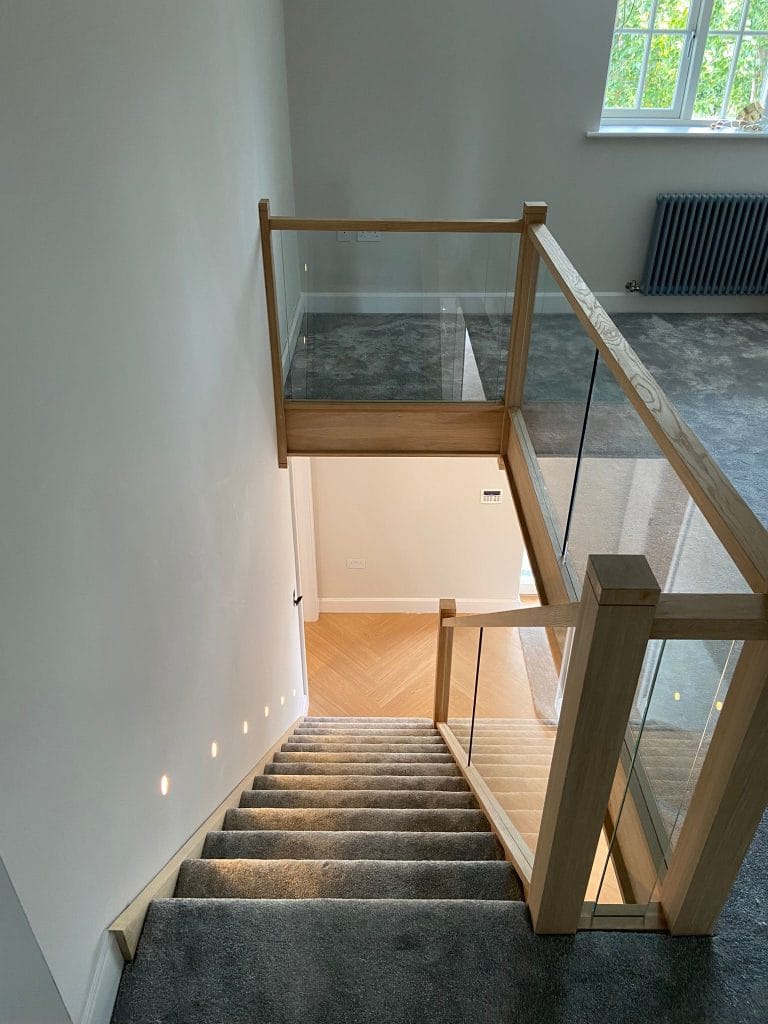 Timber and glass landing balustrade over a carpeted stairwell