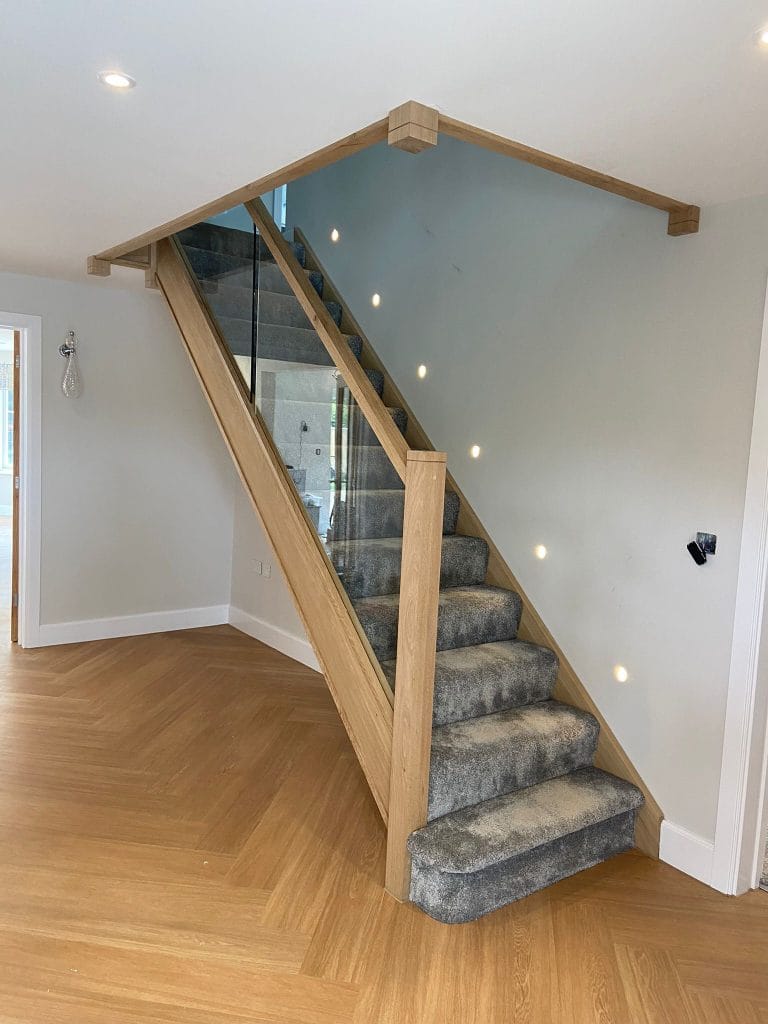 Timber and glass staircase with a grey carpet runner