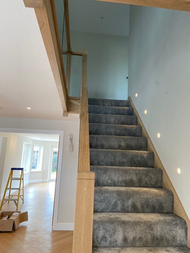 Carpeted staircase with a timber capped glass balustrade
