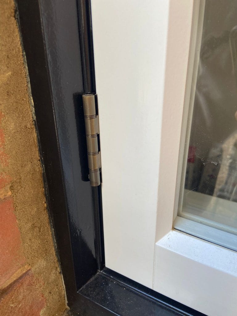 Detail of a timber window frame with brass hinge