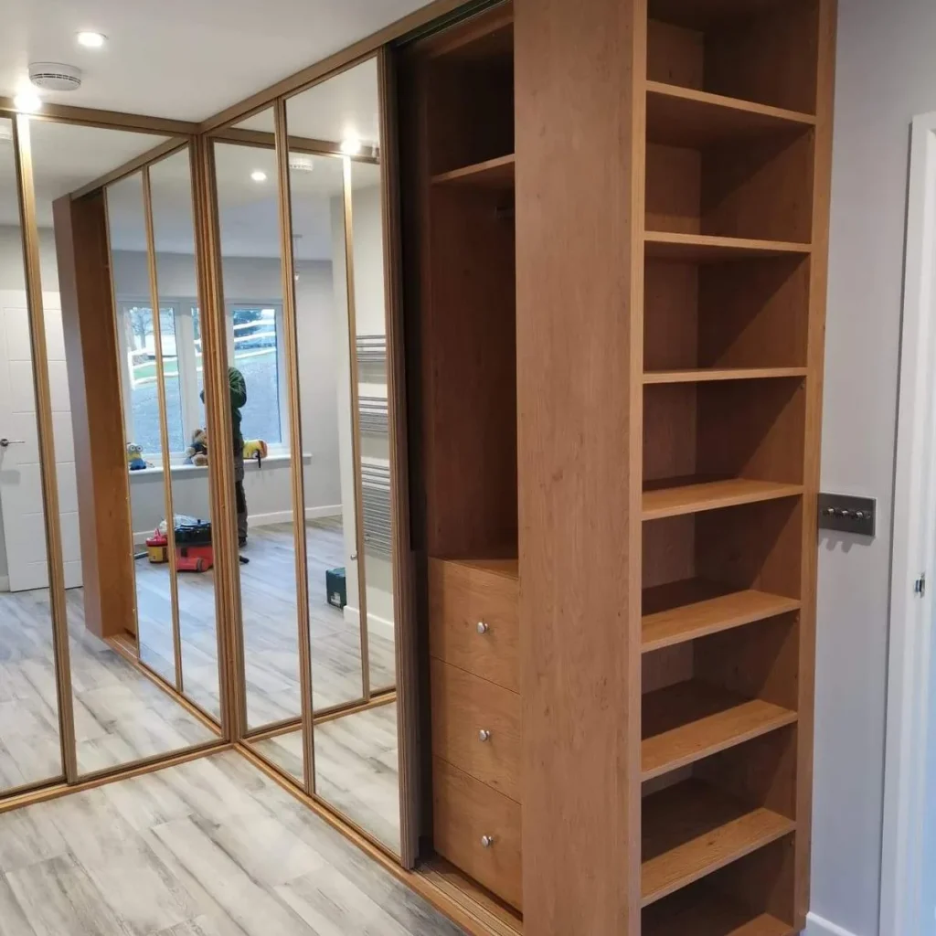 Fitted wardrobes with mirrored sliding doors and open oak shelving, made by Spittlywood